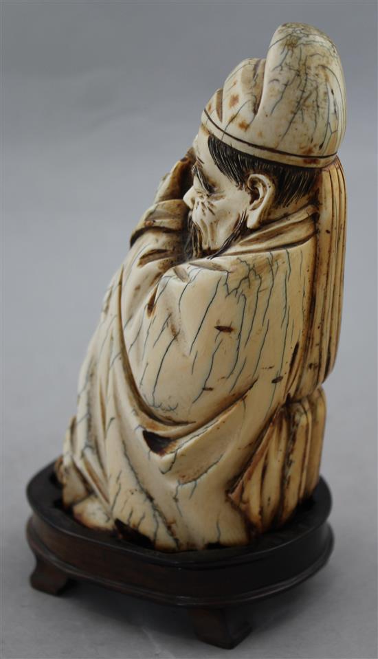 A Chinese mammoth ivory carving of a seated figure of Li Bai, holding a book, 16.5cm, wood stand